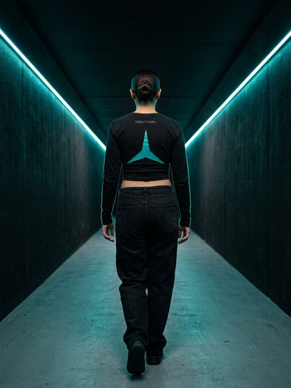 Newtral Mercedes-AMG Petronas women's long-sleeve top in black, back view, model walking down a neon tunnel
